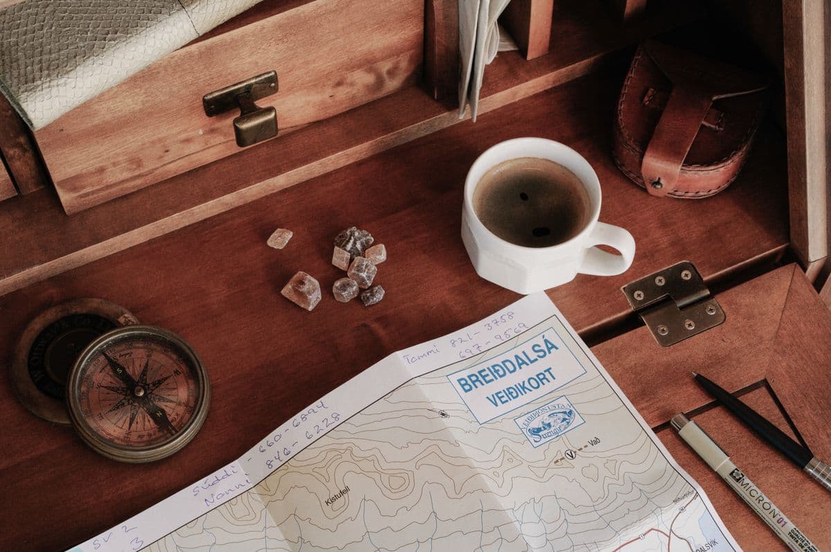 Map, compass, and coffee on a rustic wooden table